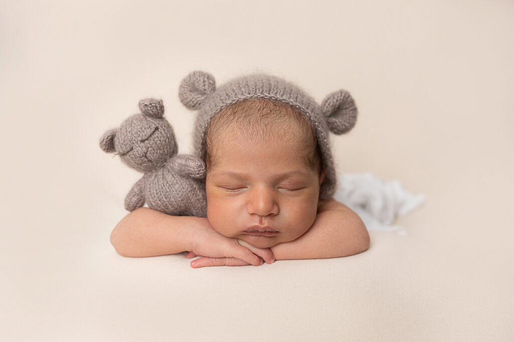 Newborn baby boy cuddling teddy bear